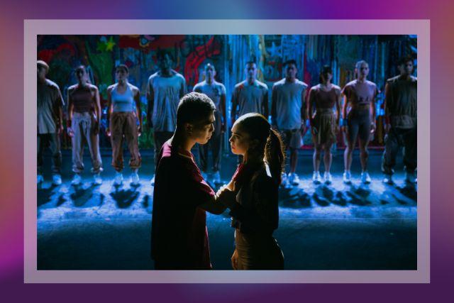 A male dancer and a female dancer face each other. A row of dancers watch the two dancers from the background