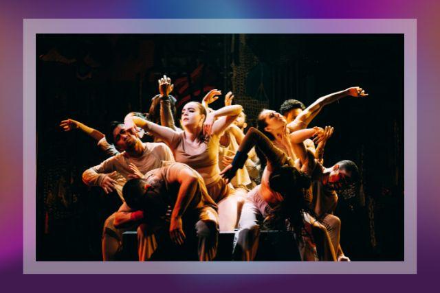 Dancers gather together in a group with their arms outstretched